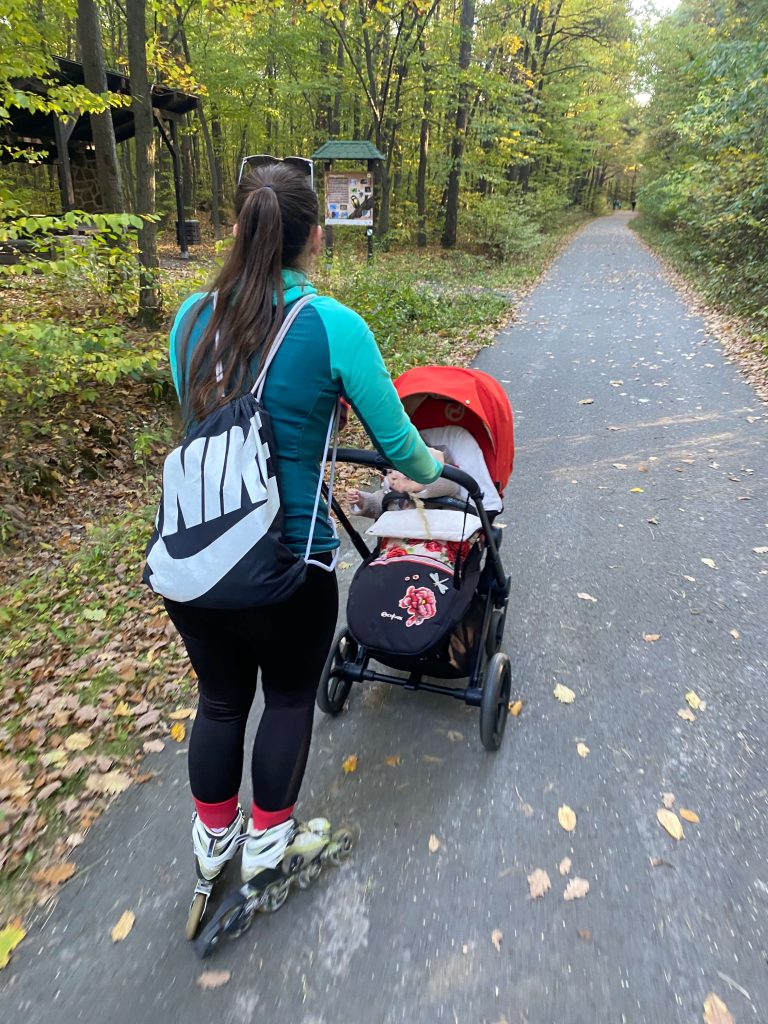 a girl rollerblading with a baby in a stroller